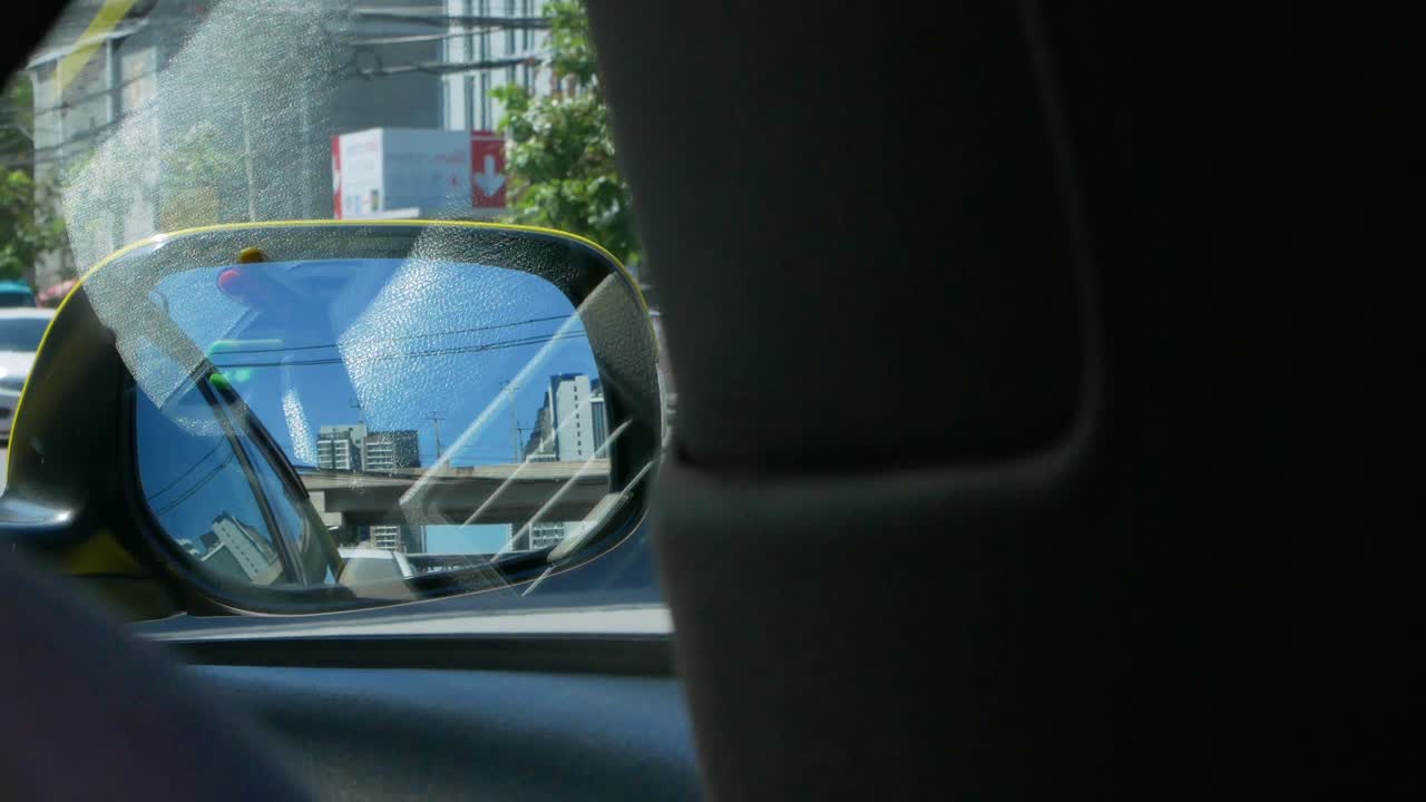 POV of side mirror of the moving car while while driving along the city of Bangkok, Thailand