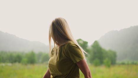 Pretty-woman-with-blonde-hair-looks-around-at-lush-field