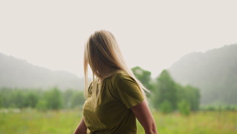 una mujer bonita con cabello rubio mira alrededor en un campo exuberante