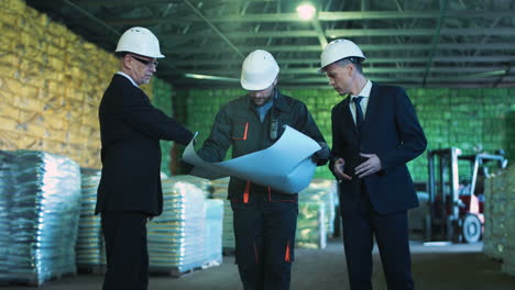 warehouse management team discussing blueprints