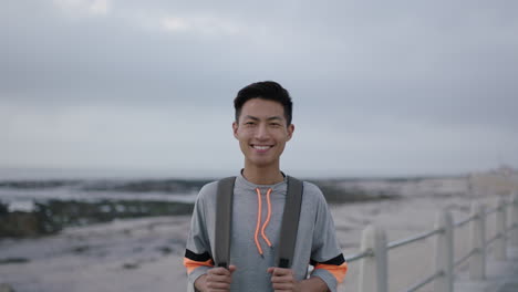 Porträt-Eines-Jungen-Asiatischen-Mannes,-Der-Glücklich-Am-Bewölkten-Strand-Am-Meer-Lächelt