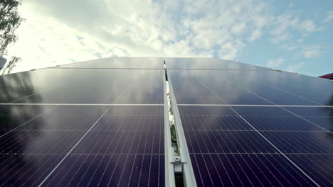 Slow-motion-across-smooth-surface-of-Solar-panels-with-a-partly-cloudy-background