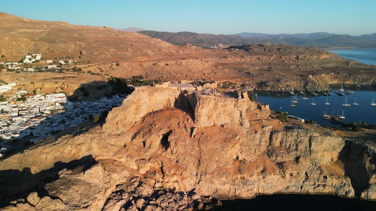Mythical Lindos Acropolis aerial drone slow approach from far at sunrise, Rhodes, Greece