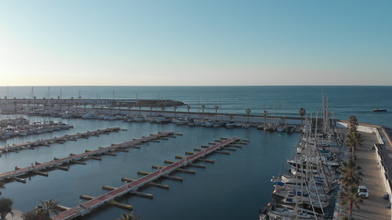 muelle ascendente de drones aéreos con yates portuarios, revela horizonte azul durante la puesta de sol