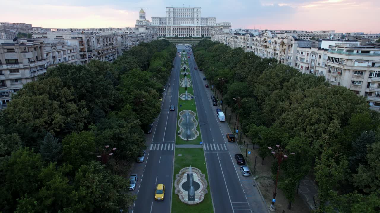 palacio del parlamento en bucarest, rumania, revelado lentamente por una toma aérea en cámara lenta con cielo naranja, vegetación exuberante y fuentes de agua bailando