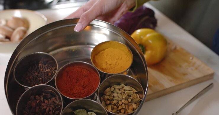 Diverse female friends with apron reacting to selfie, showing spice box for recipe demo in kitchen