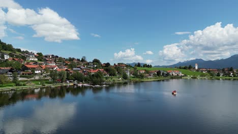 Establishing-shot-Hopfensee-lake-and-town-Hopenfen-Swabia-Bavaria-Germany-drone-aerial-view