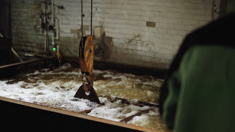 trabajador con ropa de protección vigila un proceso de extinción industrial espumoso con un gancho de grúa