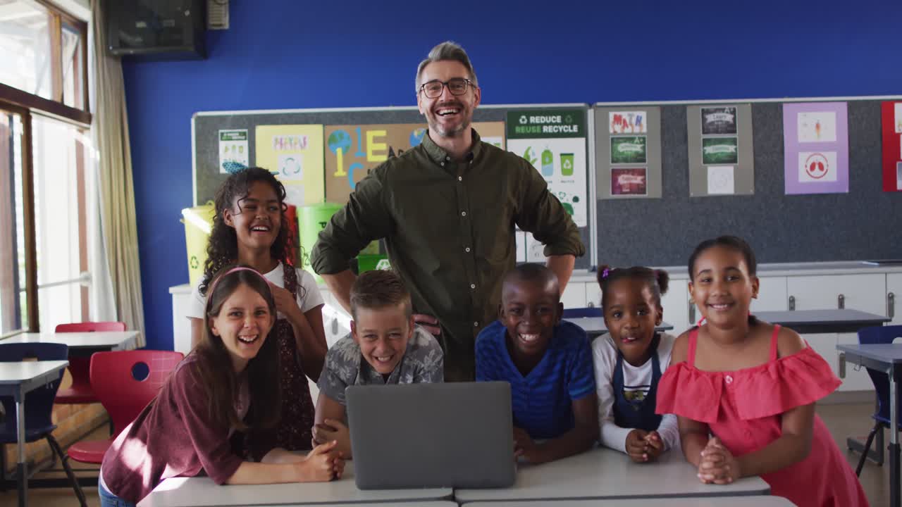 retrato de un feliz maestro varón diverso y un grupo de escolares mirando una computadora portátil
