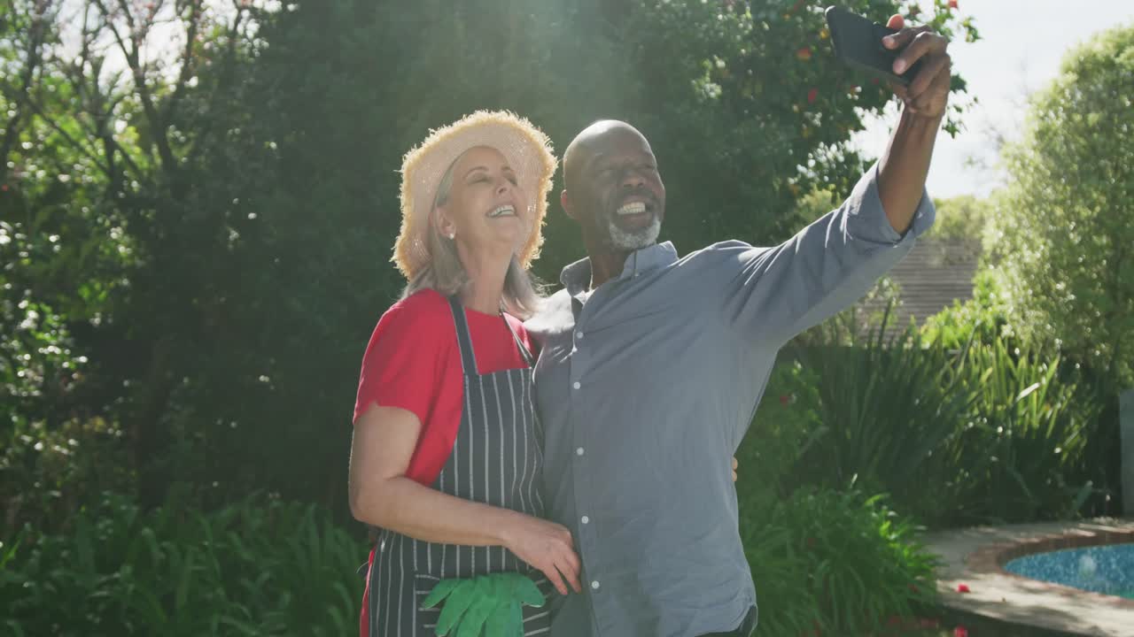 Coppie diverse senior felici che prendono selfie in giardino