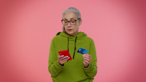 senior old stylish granny woman using credit bank card and smartphone purchases online shopping