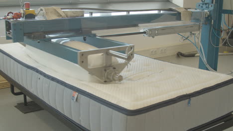 heavy roller rolling over mattress in testing facility - medium