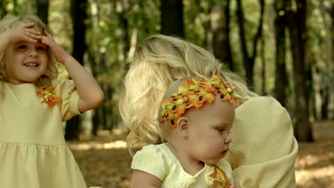 young happy mother and her children with maple in autumn park