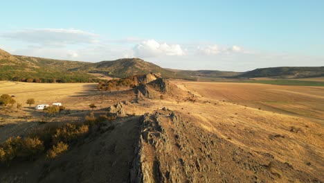 fly over rocky terrain over remote mountains near campervans