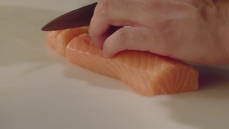 a chef carefully slices a piece of salmon with a knife in a restaurant kitchen