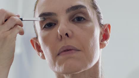 mature woman applies eyeliner and eye shadow, slow motion face closeup