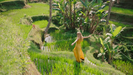 happy woman walking in rice paddy wearing yellow dress enjoying vacation exploring exotic cultural landscape travel through bali indonesia