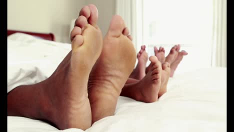 cute family wiggling toes in bed