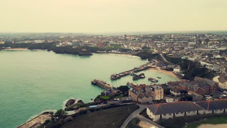 Vuelo-De-Drones-Aéreos-De-Invierno-Sobre-El-Promontorio-Que-Revela-Barcos-De-Pesca-En-El-Puerto-De-Newquay-Y-Apartamentos-De-La-Ciudad-En-El-Fondo