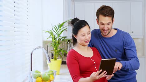 pregnant couple using digital tablet in kitchen at home 4k