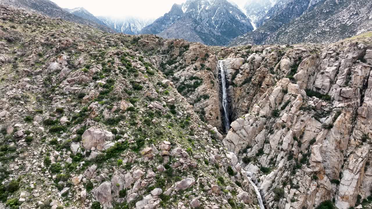 deslizarse hacia atrás vista de caída de agua con montañas en la parte posterior con nieve en el desierto ca