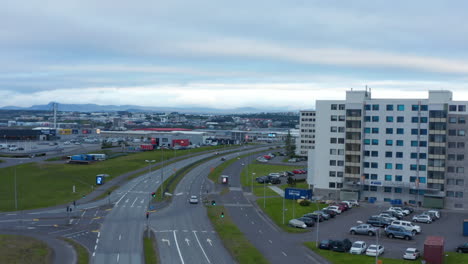 Aerial-descending-footage-of-multilane-bending-trunk-road-in-town-at-dusk.-Cars-driving-on-road.-Reykjavik,-Iceland