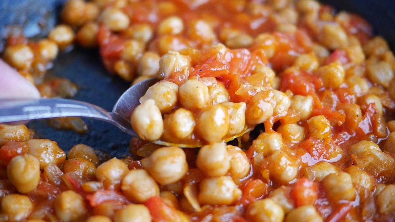 Primo piano di ceci che sobbollono in salsa di pomodoro in una padella