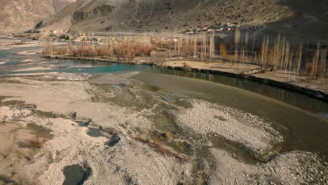 drone flying over turquoise winding river rising to reveal sweeping valley landscape of ghizer valley of gilgit baltistan