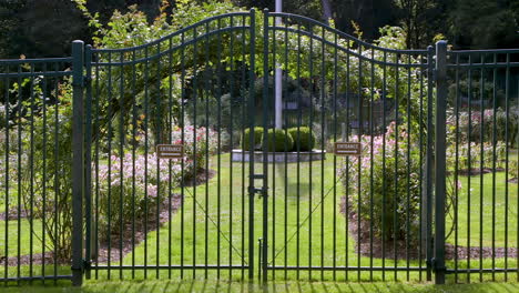 Closed-metal-gate-guarding-entrance-to-a-public-garden-on-a-sunny-and-bright-day