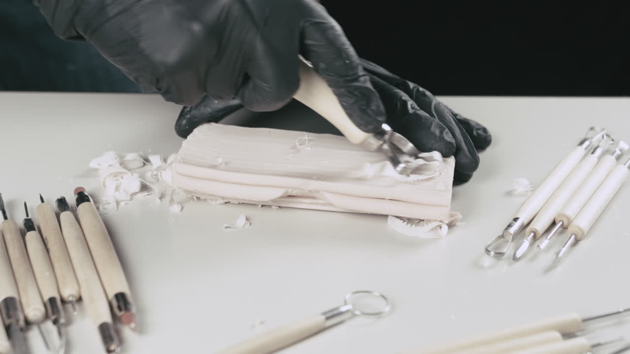 예술가는 플라스티린 조각에 루프 도구를 사용합니다.