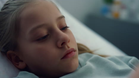 Portrait-upset-kid-lying-in-bed-holding-favorite-plush-toy-in-medical-clinic.