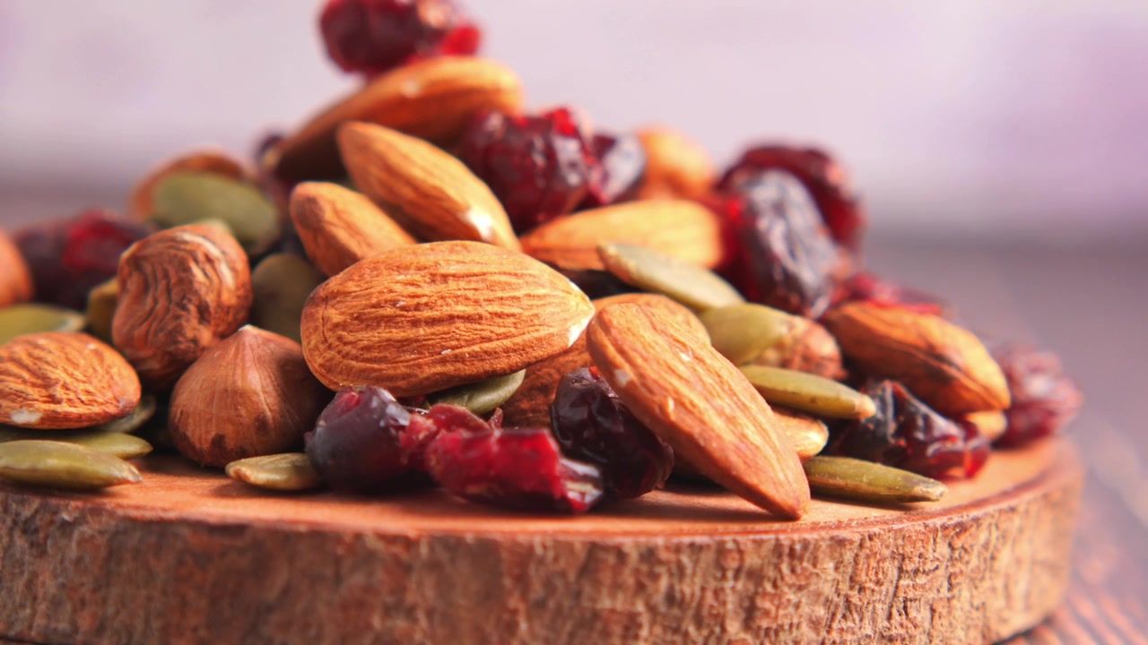 Primo piano di frutta secca mista e mirtilli rossi secchi su un tagliere di legno.
