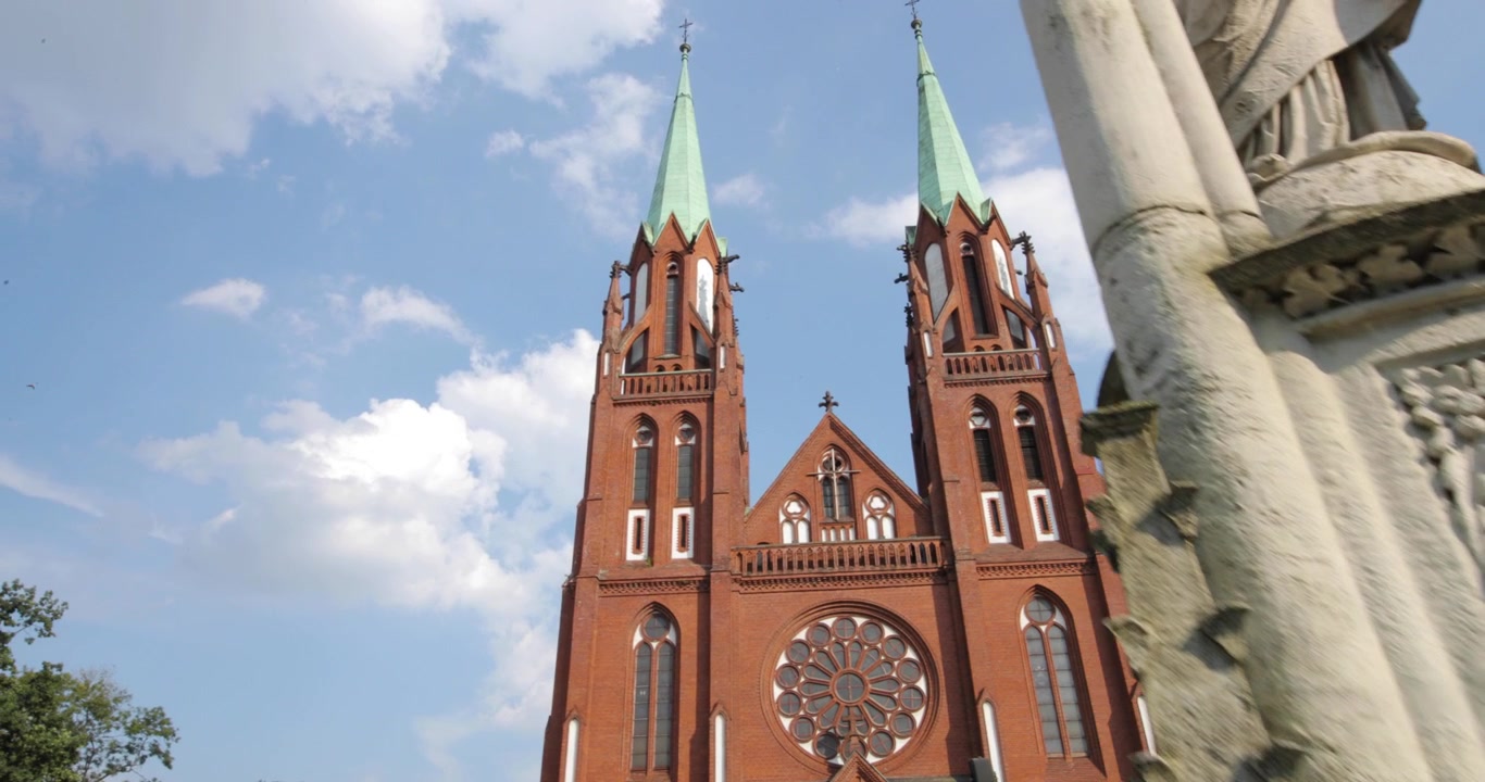 A dynamic crane shot of a Catholic church featuring a concrete monument on a sunny summer day, captured in 4K resolution