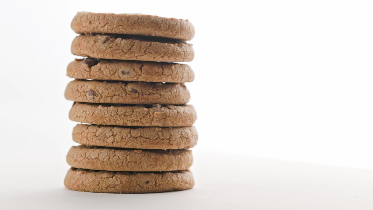 pila vertical de galletas de pastel de chips redondas con chocolate en la superficie blanca de fondo en bucle de rotación lenta