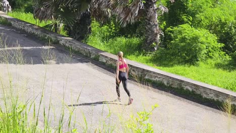 mujer caminando por un camino soleado a través de un parque