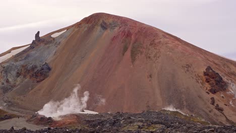 close view of the multicolored brennisteinsalda mountain, with solfataras, sulfur fumaroles, and smoke in the foreground