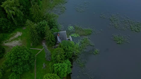 An-Aerial-View-Shot-Of-A-Green-Landscape-With-Trees-And-A-House-By-The-Lake