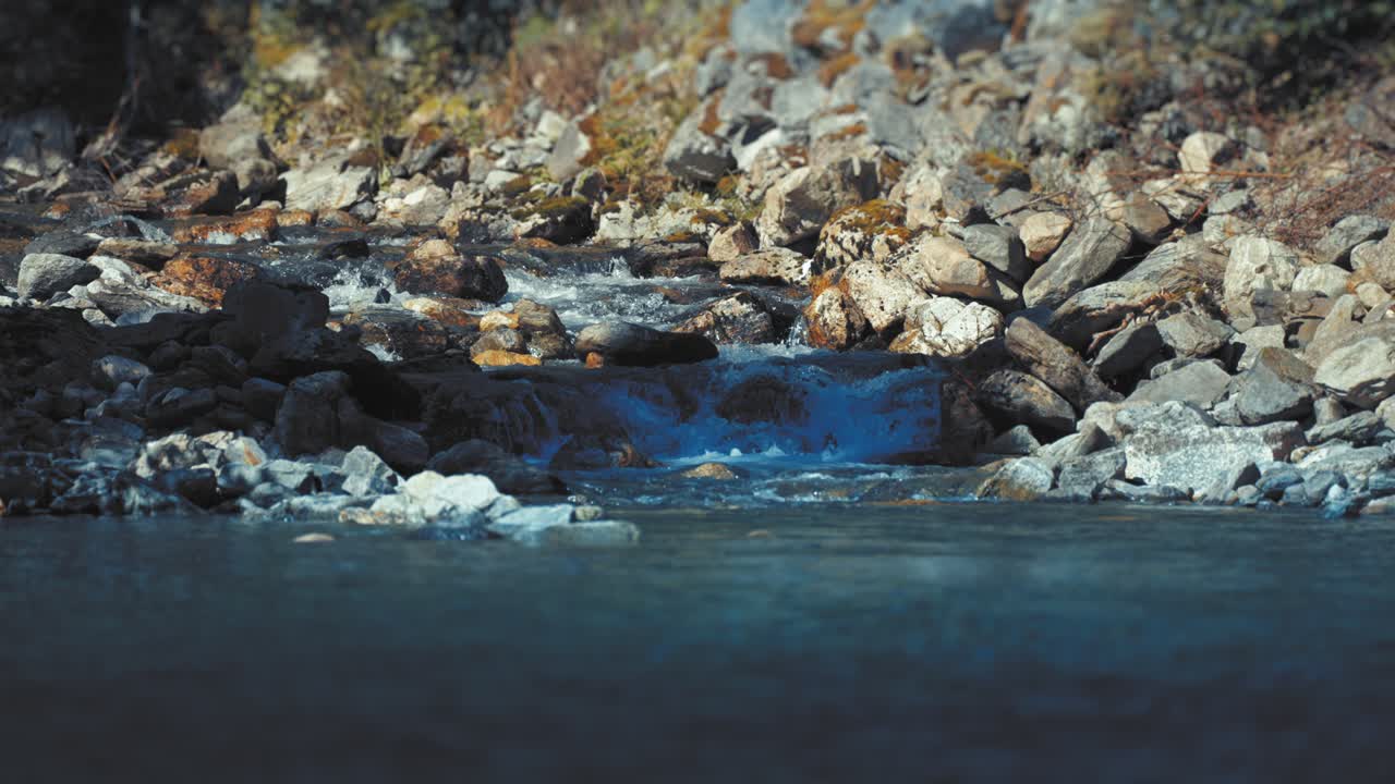 Un piccolo ruscello che scende a cascata sulla riva rocciosa sfocia nel fiordo di Naeroy.
