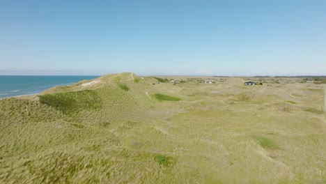 una vista aérea de casas pequeñas se alzan entre dunas de arena altas y cubiertas de hierba