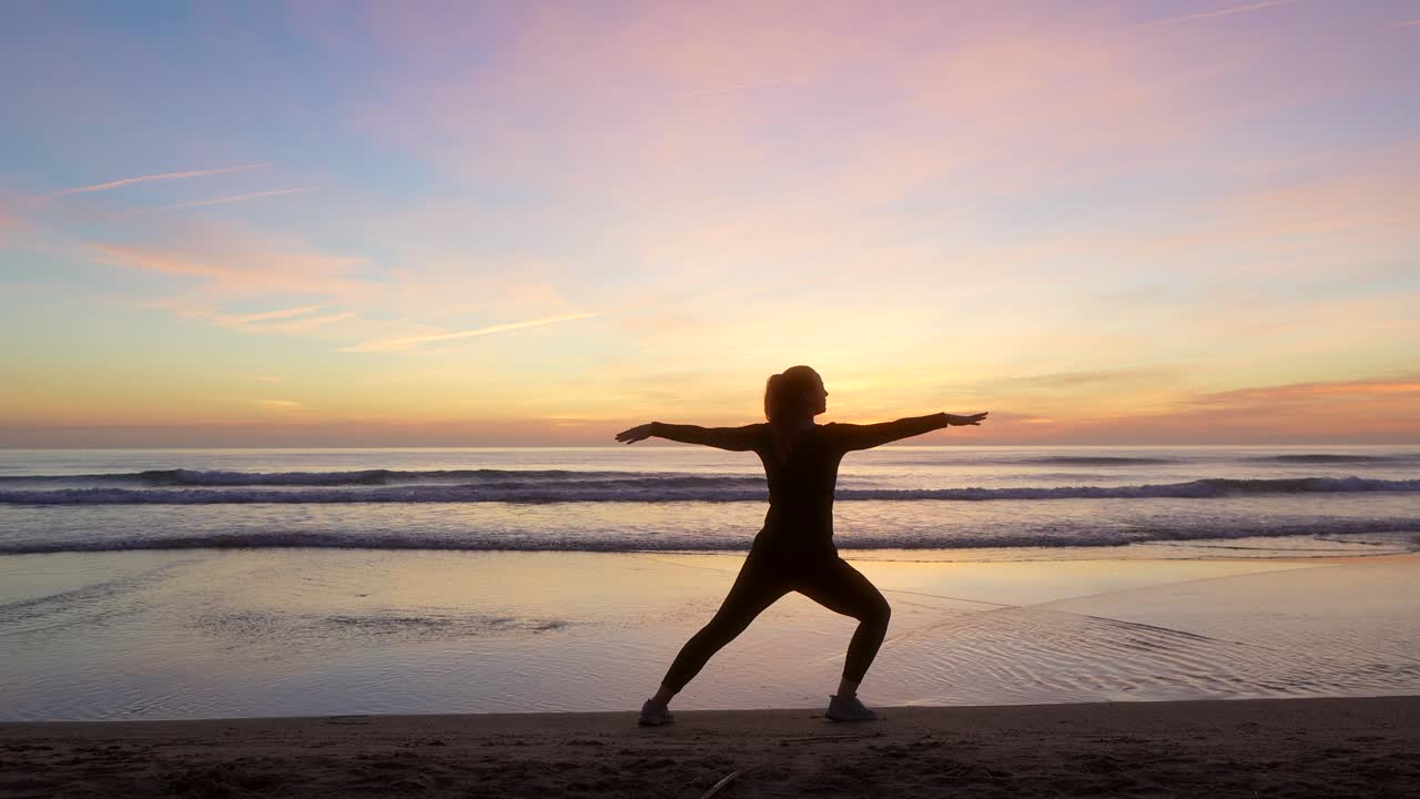 silueta de una mujer haciendo una pose de guerrero dos mirando hacia el mar