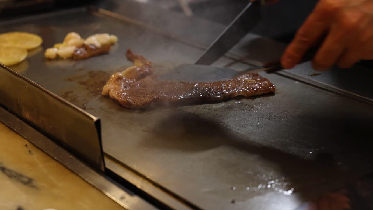 요리사는 뜨거운 그릴에서 스테이크를 능숙하게 준비합니다.