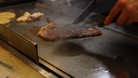 chef skillfully prepares steak on hot griddle