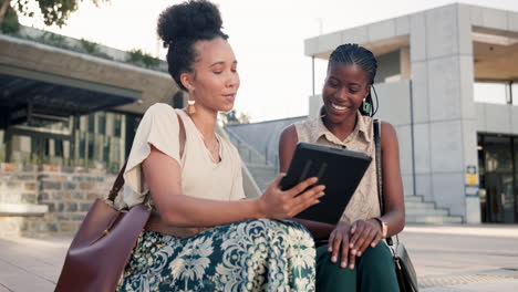 two young women looking at a tablet outdoors