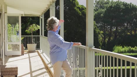 Lächelnde-Kaukasische-Seniorin-Zu-Hause,-Die-Vom-Balkon-Aus-Den-Blick-Auf-Den-Sonnigen-Garten-Genießt