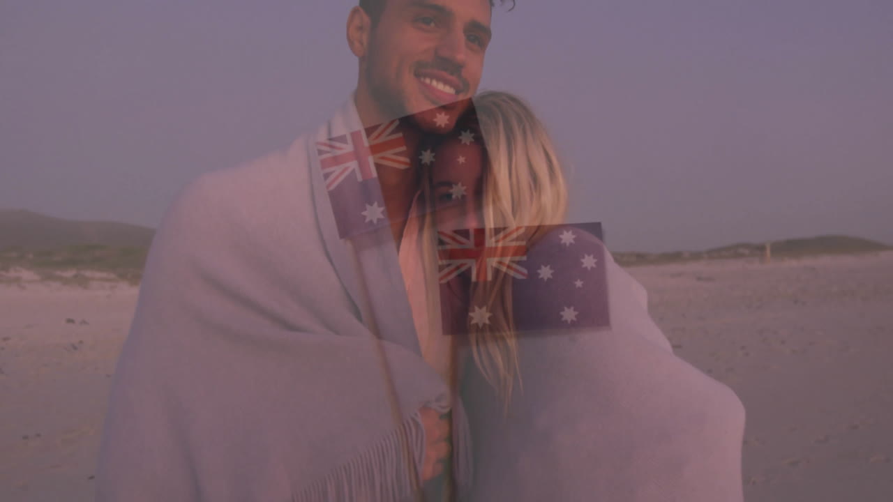 Wrapped in blanket, couple on beach with animation of Australian flag overlay