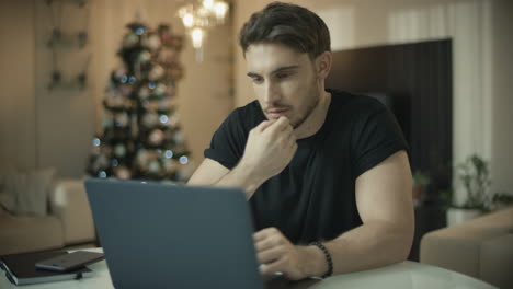 male person using laptop in home at christmas holiday. man working on computer