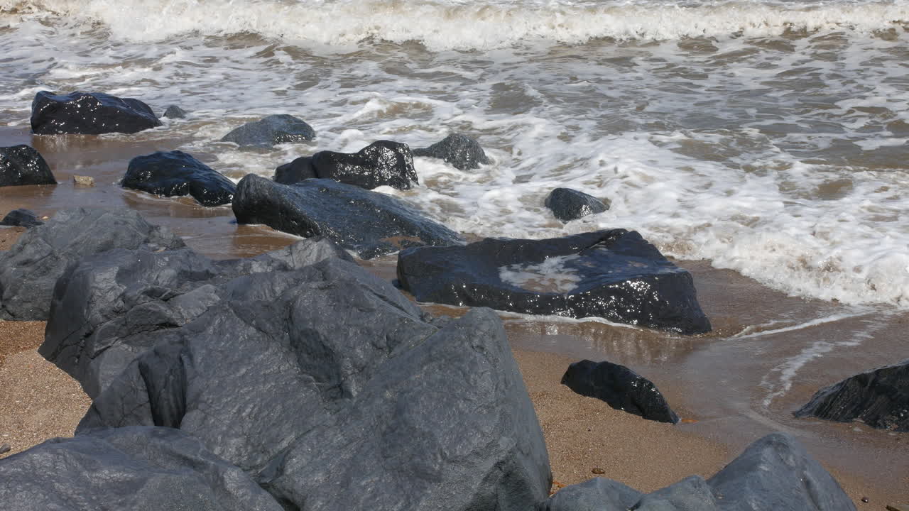Onde del mare che si infrangono sugli scogli della spiaggia