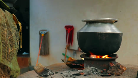 a aluminium pot is placed on a traditional fireplace with burned woods