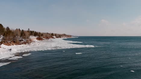 Frozen-Coast-And-Calm-Ocean-Waters-Of-Duluth-Minnesota-in-Winter---aerial-shot