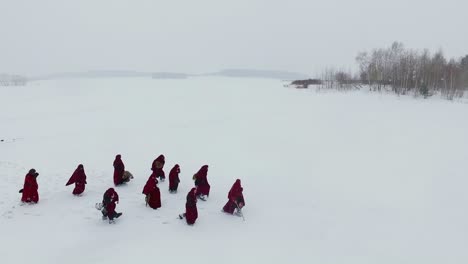 people in red cloaks on a frozen lake